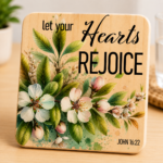 Inspirational wooden coaster featuring the Bible verse reference John 16:22 and the phrase "Let Your Hearts Rejoice" surrounded by elegant cherry blossom flowers, delicate buds, and lush green foliage. Faith-based Christian coaster with watercolor botanical artwork and natural wood finish, perfect for Christian home décor, religious gifts, prayer spaces, Bible study groups, and daily inspiration.